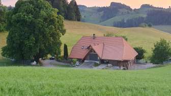 Bauernhaus von Aussen mit Huegeln in der Aussicht