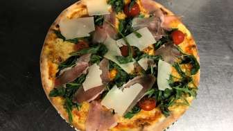 Pizza mit Kaese, Rohschinken, Tomaten und Rucola